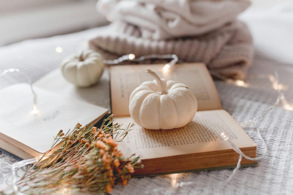 white autumn aesthetic. folded sweaters, tiny white pumpkins, old books, fairy lights and dried flowers